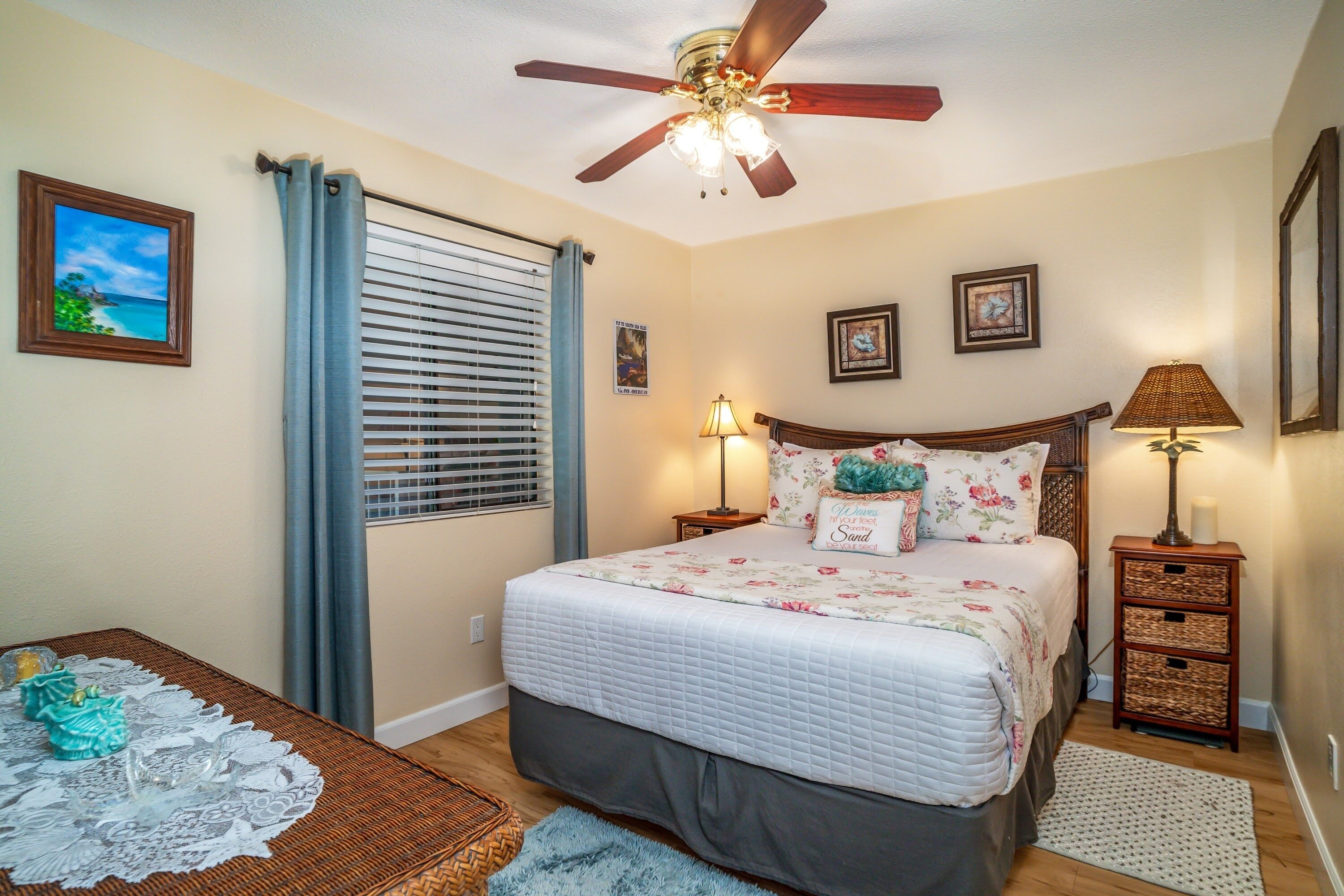 A bedroom with a bed, ceiling fan, bedside lamps, and a window with curtains.