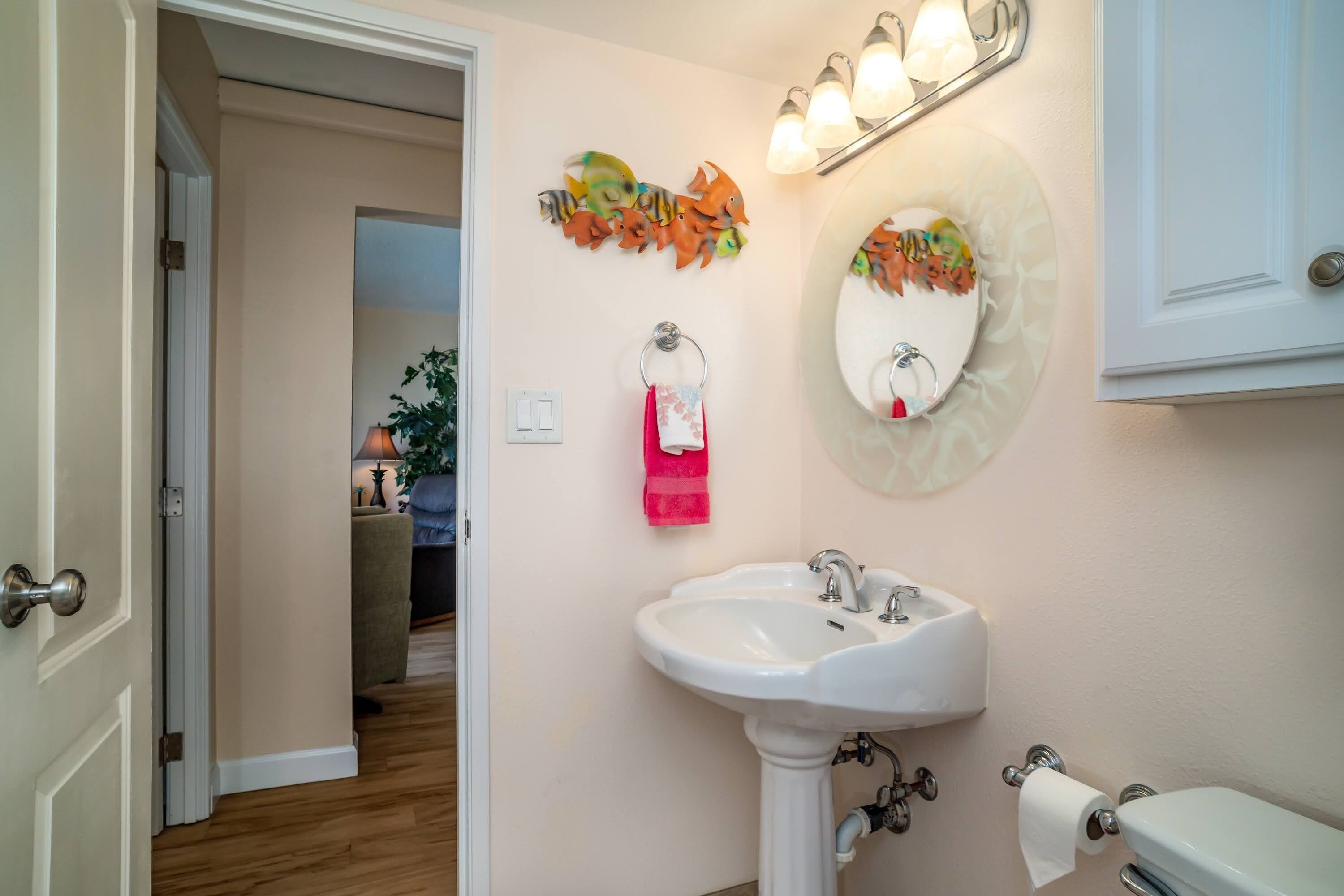 Une salle de bain équipée d’un lavabo, de toilettes et agrémentée d’œuvres d’art décoratives sur les murs.