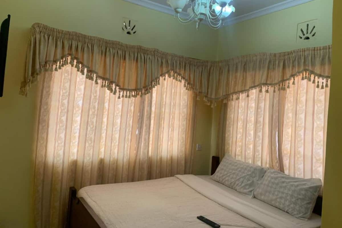 A bedroom with a bed, curtains, and a chandelier.