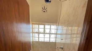 Un baño con ducha, paredes de azulejos y una ventana.