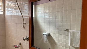 Un baño con ducha, paredes de azulejos, un perchero y una ventana con marco de madera.