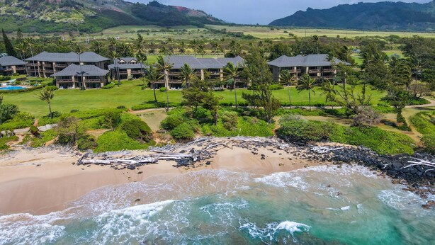 Un resort con diversi edifici, una spiaggia e montagne sullo sfondo.