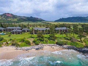A resort with multiple buildings, a beach, and a mountainous backdrop. - Kauai Kaha Lani by Coldwell Banker Island Vacations (Lihue)