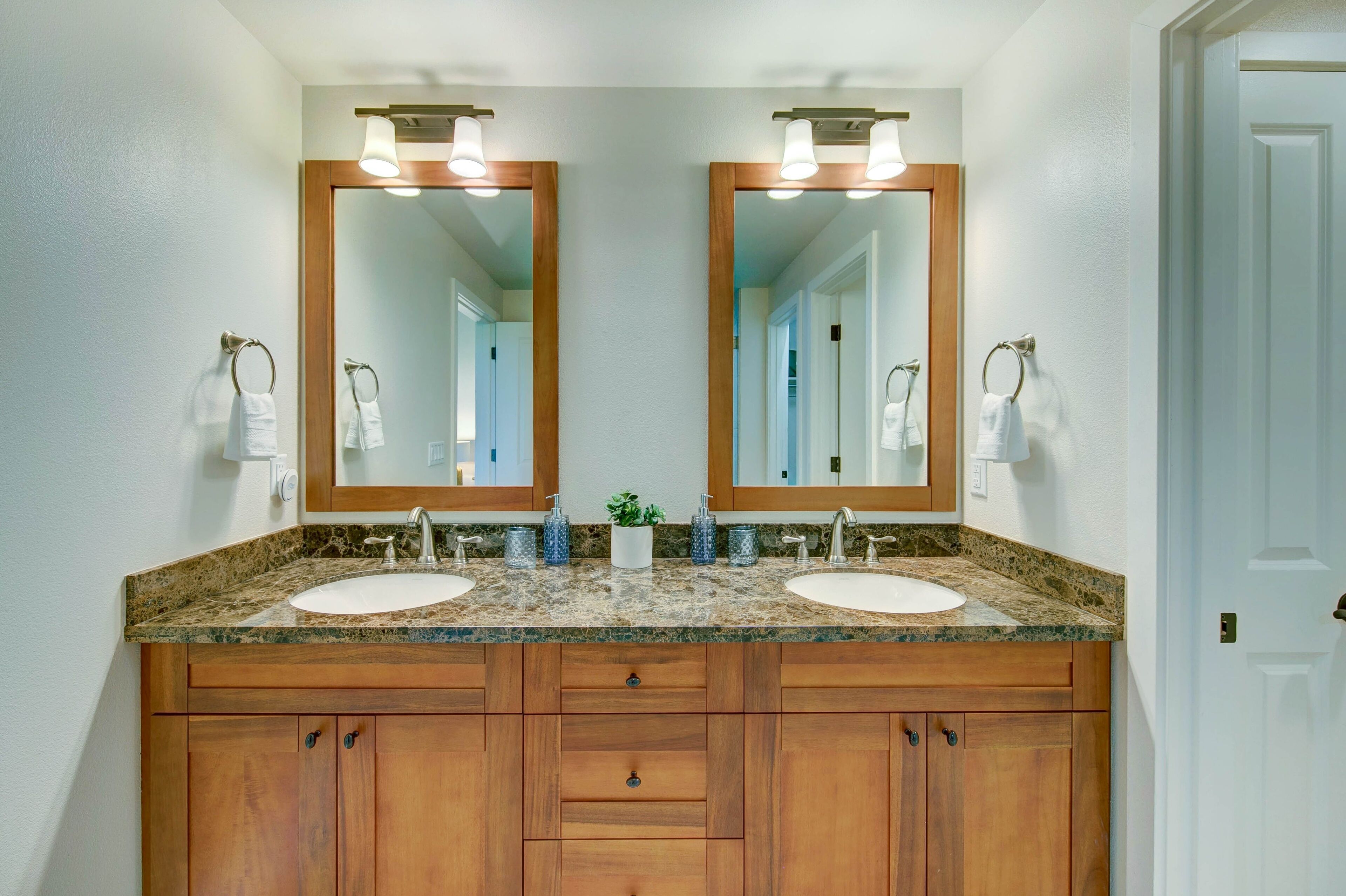 A bathroom with two sinks, wooden cabinets, and a large mirror with lights.