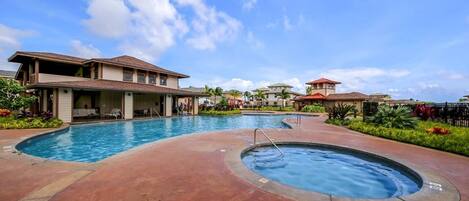Zona de piscina con jacuzzi, rodeada de edificios con un área de descanso junto a la piscina y vistas al cielo.