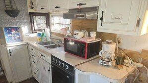 Une cuisine compacte équipée d’un évier, d’un four à micro-ondes, d’une cuisinière et d’une machine à café.