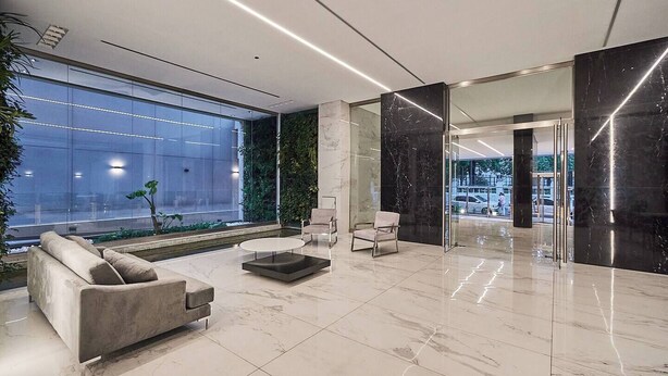 En moderne lobby med sofa, stole, sofabord og et stort vindue.