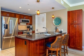 A modern kitchen with a large island, stainless steel appliances, wooden cabinets, and a decorative backsplash.