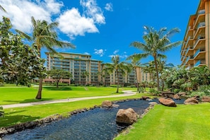 A hotel with a swimming pool, palm trees, and a well-maintained lawn. - Honua Kai Hokulani 310 2 Bedroom Condo (Lahaina)