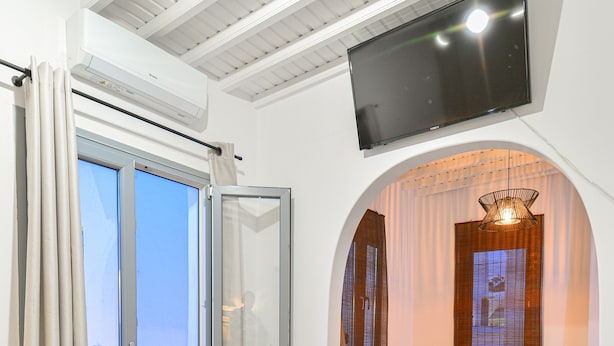A bedroom with a bed, a sofa, a TV, and a balcony.
