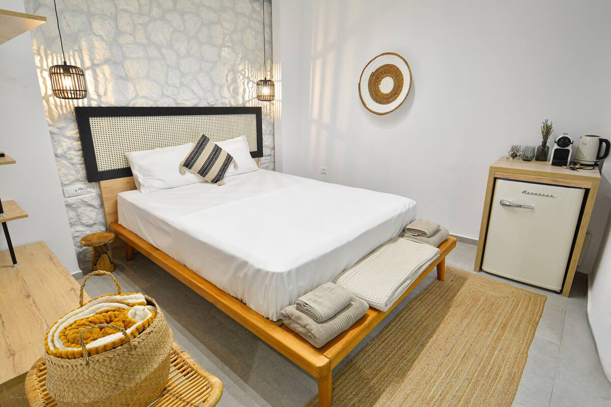 Een keurig opgemaakte slaapkamer met een bed, nachtkastjes, een klein kastje en een geweven mand.