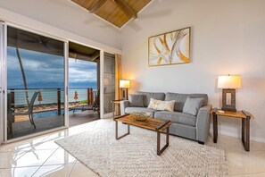 A living room with a grey sofa, two side tables with lamps, a wooden coffee table, and a large abstract painting on the wall. - Hale Kai by Coldwell Banker Island Vacations (Lahaina)