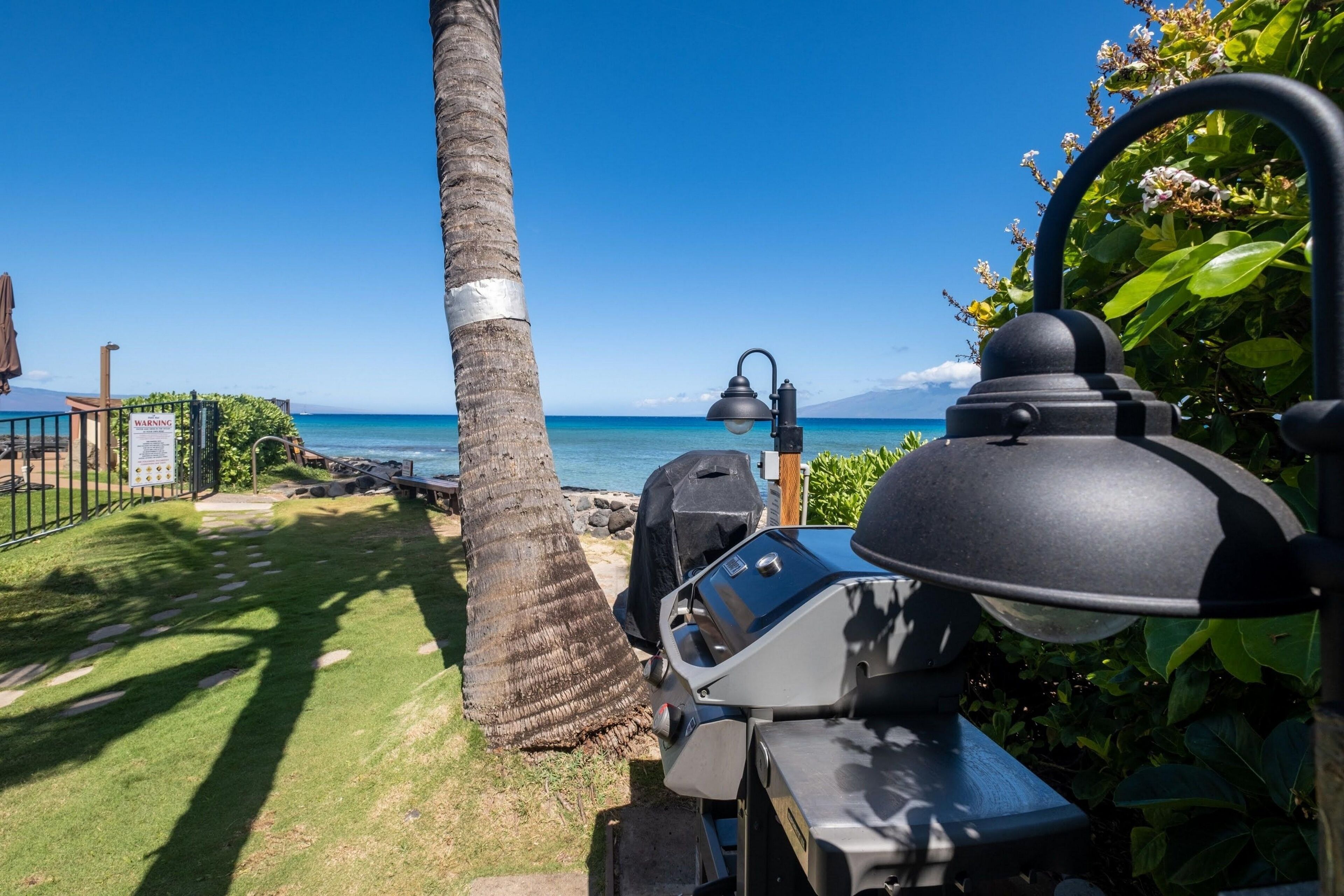 A patio area with a grill, a lamp, and a view of the ocean.
