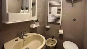 Een moderne badkamer met een wastafel, toilet, bidet en een handdoekhouder.
