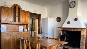 Een keuken met houten kasten, een eettafel met stoelen, een inbouwfornuis en een klok aan de muur.