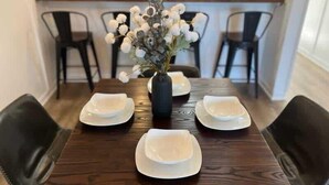 Een eettafel met vier witte borden en een bloevas.