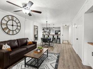 Relax in this stylish living space with a large wall-mounted clock, leather sofa, and patterned rug.