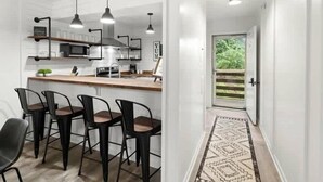 Een moderne keuken met een centraal kookeiland, barkrukken, hanglampen en uitzicht op een groen buitenlandschap.