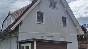 A two-story house with a sloped roof, a garage, and a small porch. - Doppelhaushälfte für 6 Personen mit Wlan (Graal-Müritz)