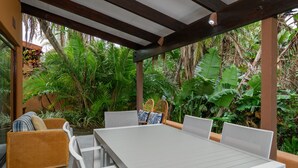A covered patio with a dining table and chairs, surrounded by lush tropical plants. - San Lameer Villa 3204 (Southbroom)