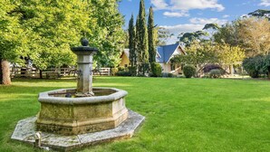 A stone fountain in a well-manicured lawn with a house in the background. - Glen Regan, Berrima, Southern Highlands (Berrima)