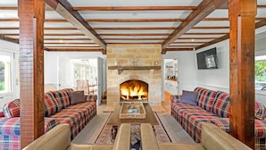 A cozy living room with a stone fireplace, two plaid sofas, and a wooden ceiling structure. - Glen Regan, Berrima, Southern Highlands (Berrima)