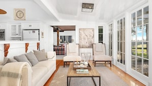 A spacious living room with a large window, a fireplace, and a dining area with a wooden table. - Glen Regan, Berrima, Southern Highlands (Berrima)