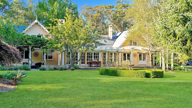 A two-story house with a covered patio, a lawn, and a variety of trees. - Glen Regan, Berrima, Southern Highlands (Berrima)