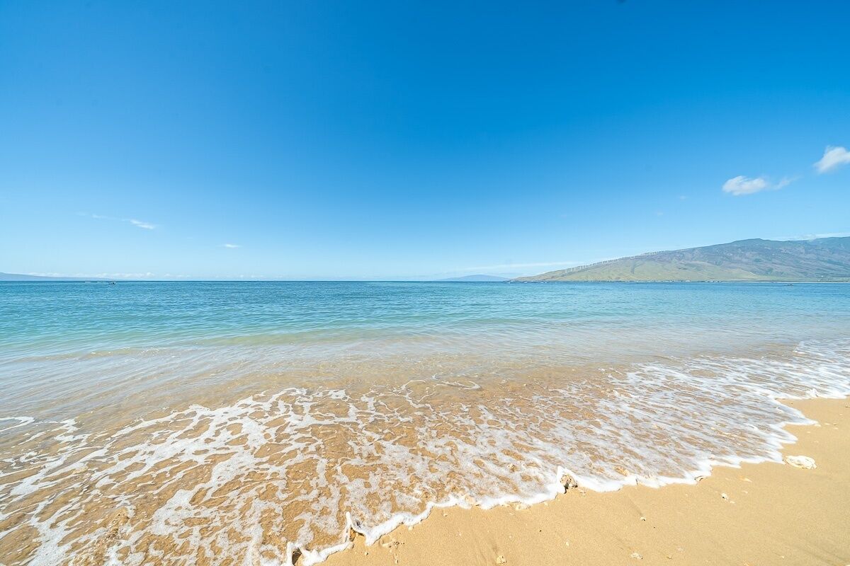 A beach with clear blue water and a sandy shore.
