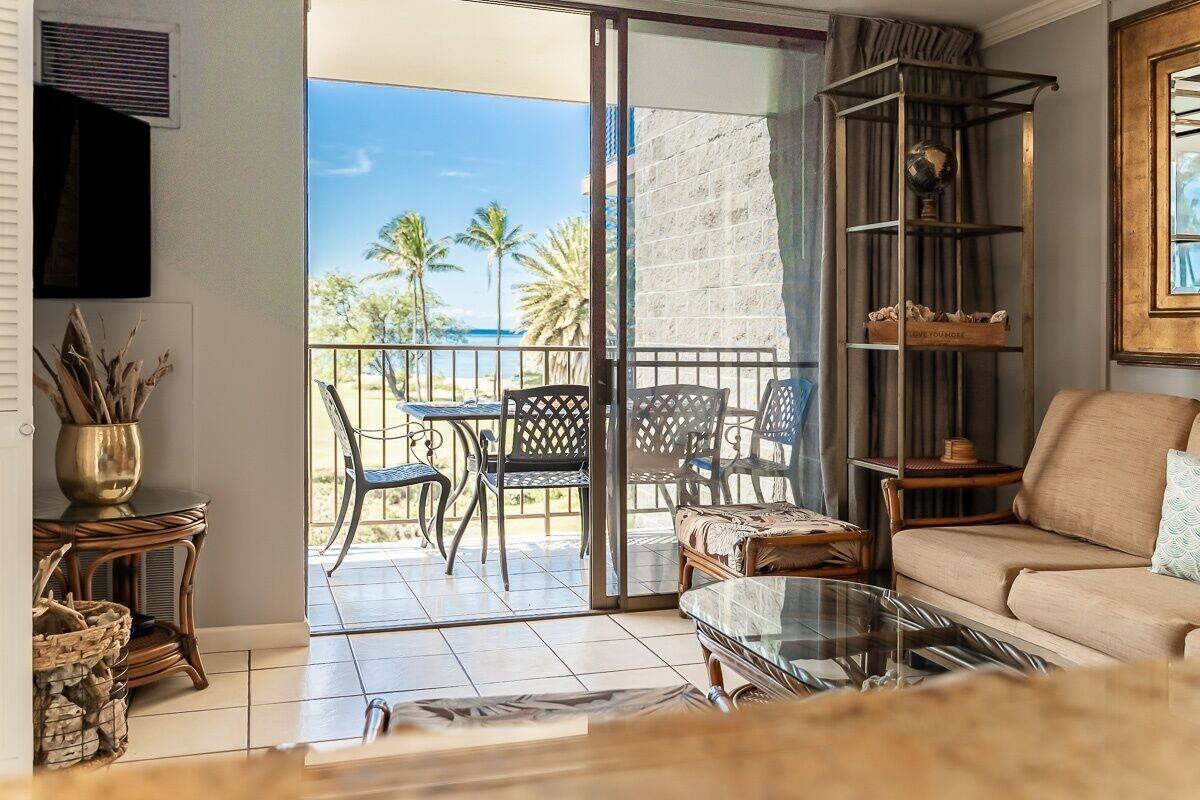 Un salon avec un canapé, une table basse en verre et un balcon équipé de chaises et d’une table.