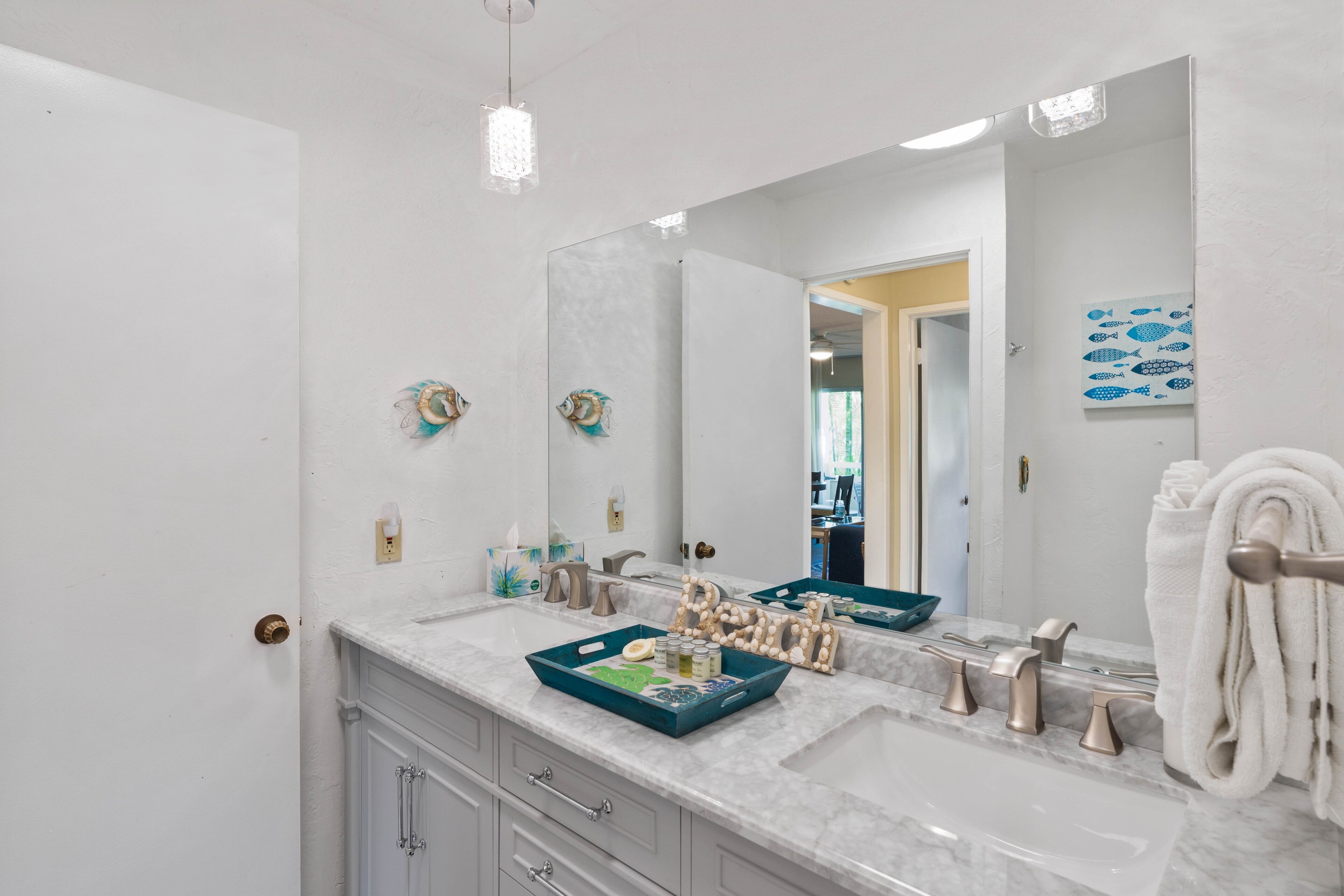 A bathroom with a white vanity, a large mirror, and a towel rack.