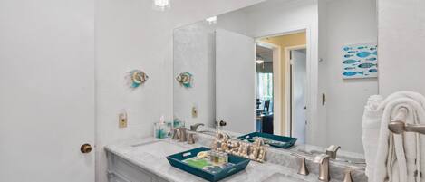 A bathroom with a white vanity, a large mirror, and a towel rack.