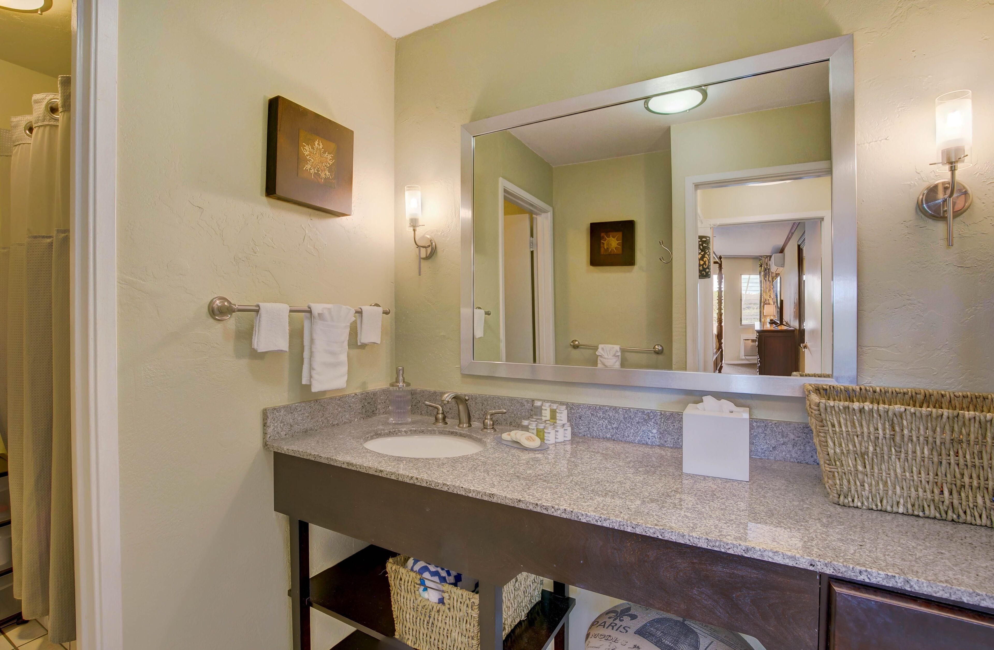 A bathroom with a granite countertop, two sinks, a large mirror, and a towel rack.