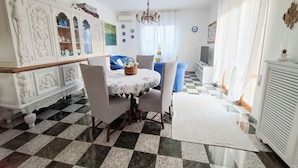 A dining area with a checkered floor, a chandelier, and a television on a stand.