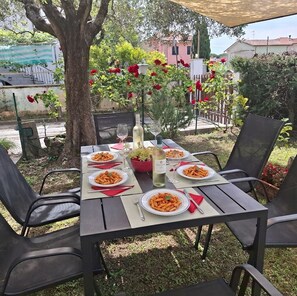 An outdoor dining table set with plates of pasta, wine glasses, and a bottle of wine, surrounded by chairs. - By the sea, 3 bedrooms, garden, and private parking, near Lerici and Cinque Terre (Fiumaretta di Ameglia)