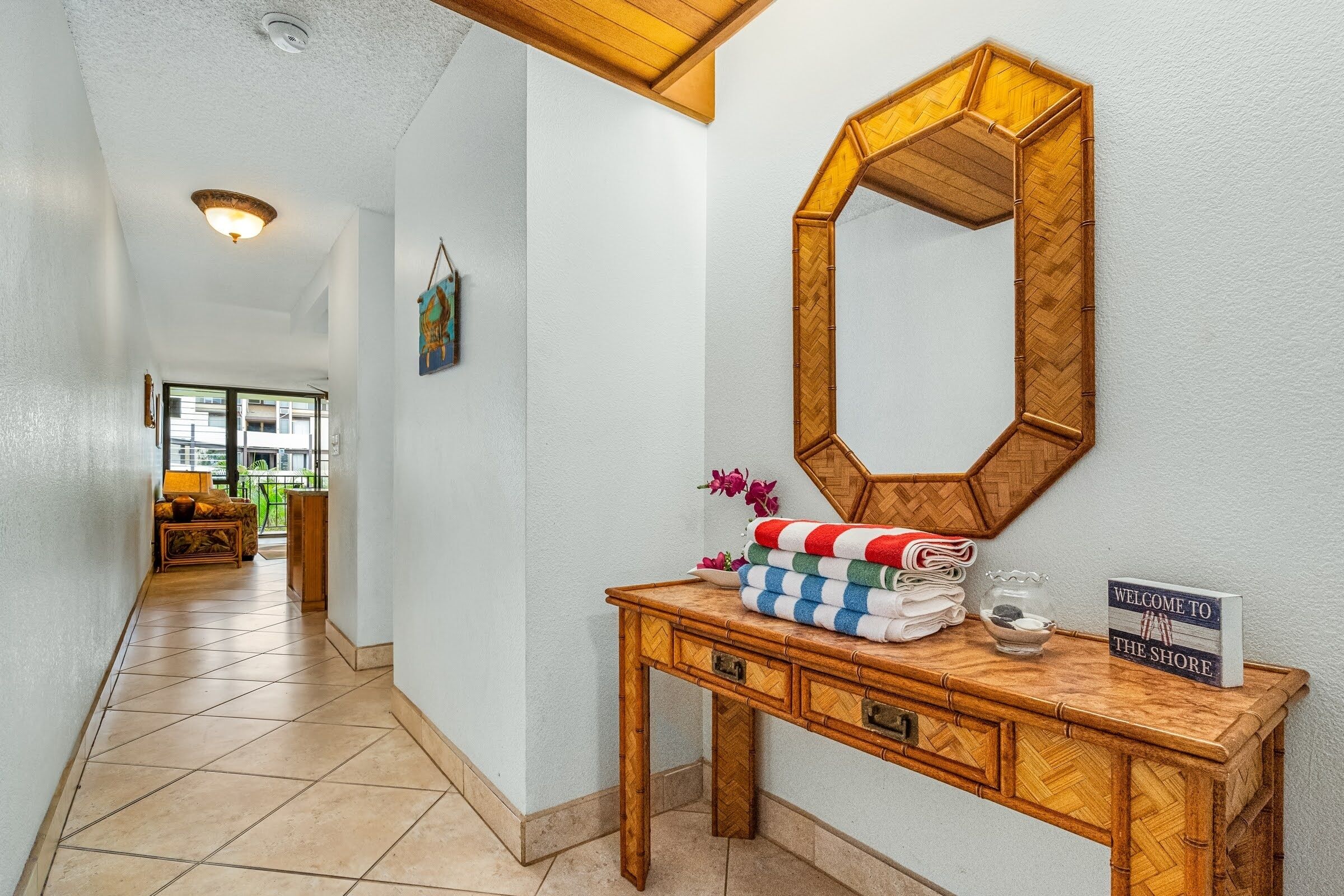 Un couloir avec une console en bois, un miroir et une pancarte de bienvenue.