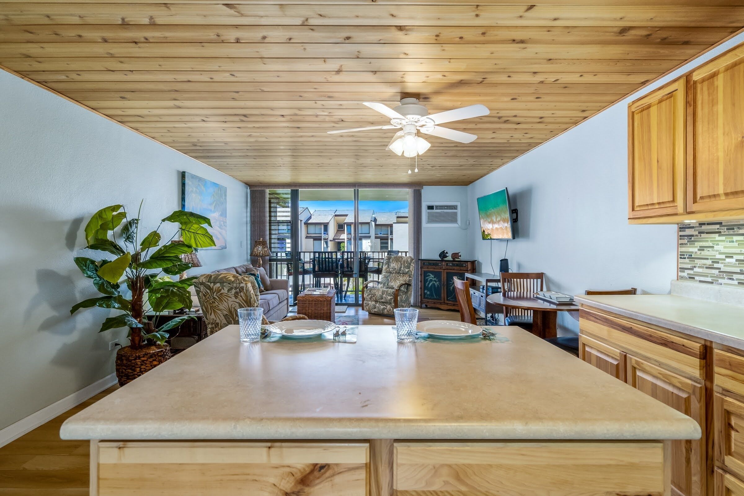 A spacious kitchen with wooden cabinets, a central island, and a ceiling fan.
