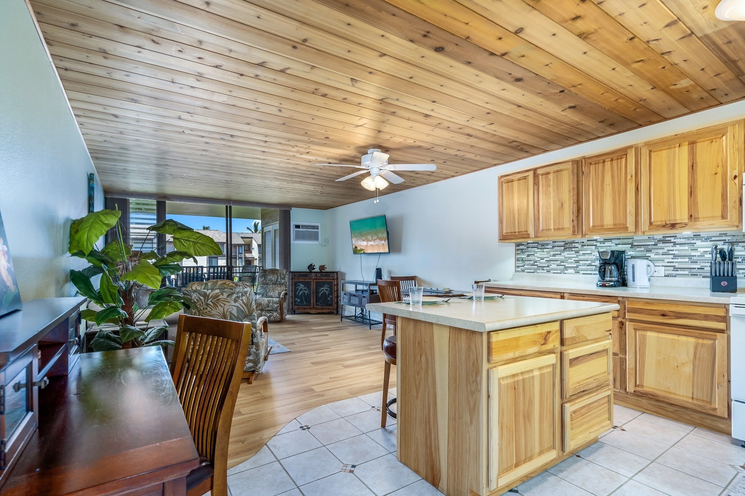A spacious kitchen with wooden cabinets, a central island, and a ceiling fan.