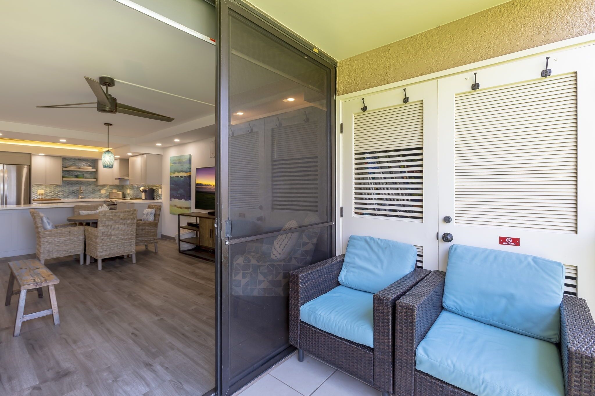 Ein modernes Interieur mit Glastür zum Balkon, Korbm öbeln und Deckenventilator.
