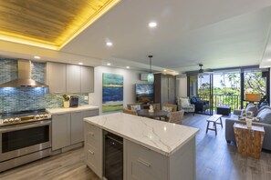 A modern kitchen with a large island, stainless steel appliances, and a view to the outdoor patio area.