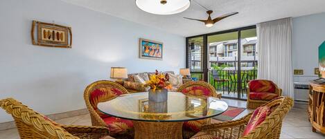 A dining area with wicker furniture, a glass table, and a ceiling fan.