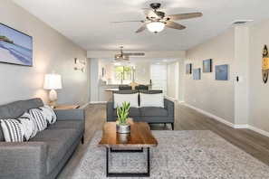 A modern living room with a gray sofa, a wooden coffee table, and a ceiling fan. - Big Island Holualoa Bay Villas by Coldwell Banker Island Vacations (Kailua-Kona)