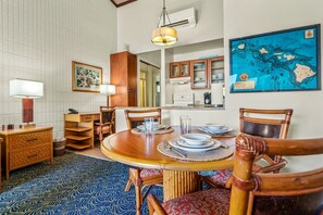Un coin repas avec une table ronde en bois, des chaises et une carte accrochée au mur.