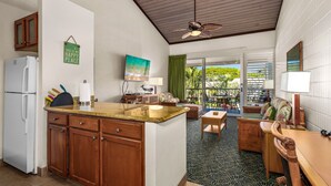 A compact kitchen with wooden cabinets, a white refrigerator, and a granite countertop. - Napili Shores by Coldwell Banker Island Vacations (Lahaina)