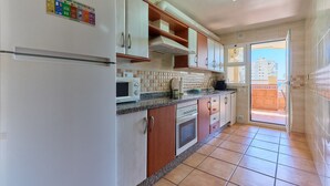 A kitchen with white cabinets, a microwave, and a refrigerator.