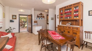 A dining area with a wooden table and chairs, a red rug, and a cabinet with glass doors.