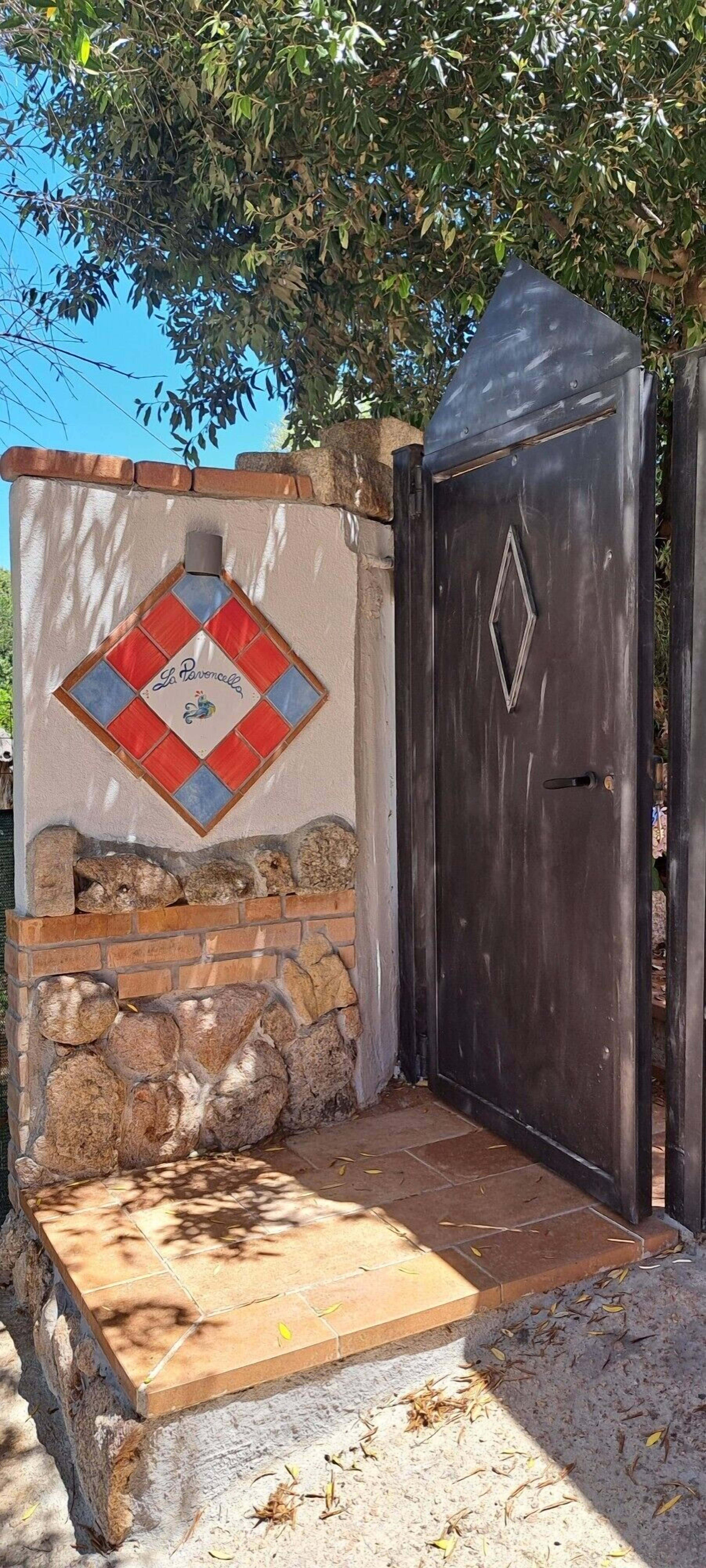 Ein begrenzter Eingang mit einer Steinmauer, einer gefliesten Terrasse und einer Zierwand mit Rautenmuster.