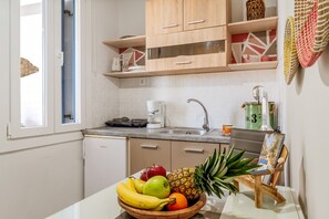 A kitchen with a fruit bowl, a coffee maker, and a sink.