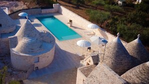 Una piscina con arquitectura de piedra y sombrillas.