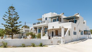 A white building with balconies, a tree, and a clear sky. - Holiday Home 'Porto Galini Tinos Perastra 103' with Sea View, Wi-Fi and Air Conditioning (?a??t?)